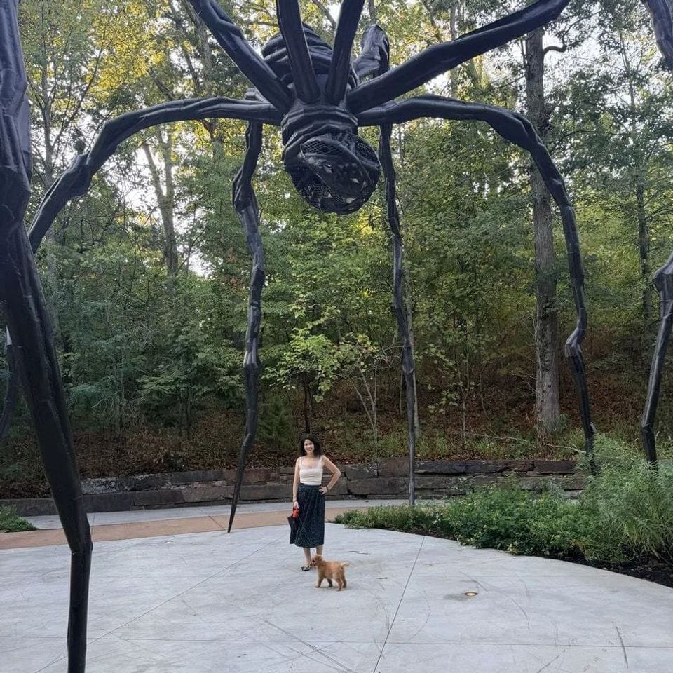 Our founder walking a puppy on a leash beneath the giant spider sculpture at Crystal Bridges